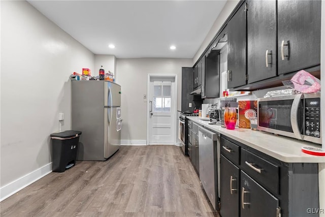 kitchen featuring baseboards, light wood-type flooring, light countertops, stainless steel appliances, and dark cabinets