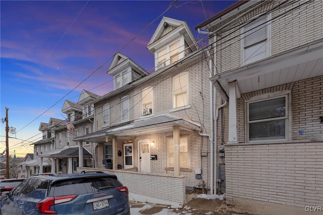 view of front of home featuring covered porch and brick siding