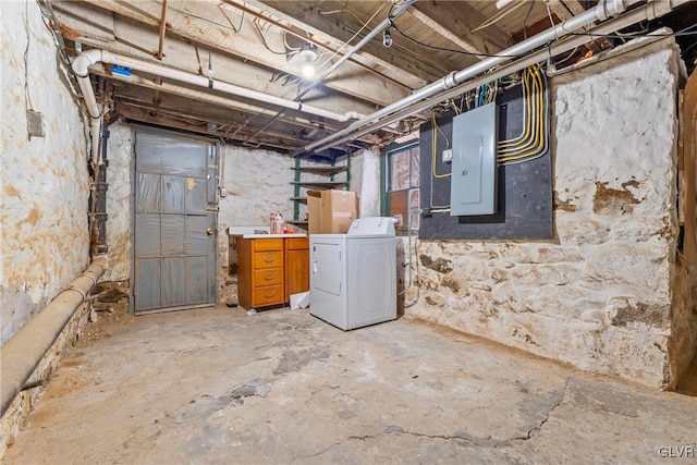 unfinished basement featuring electric panel and washer / clothes dryer