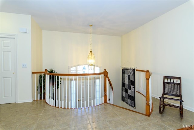 hallway featuring tile patterned floors, baseboards, an upstairs landing, and a notable chandelier