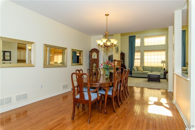 dining space with visible vents, baseboards, an inviting chandelier, and light wood-style flooring