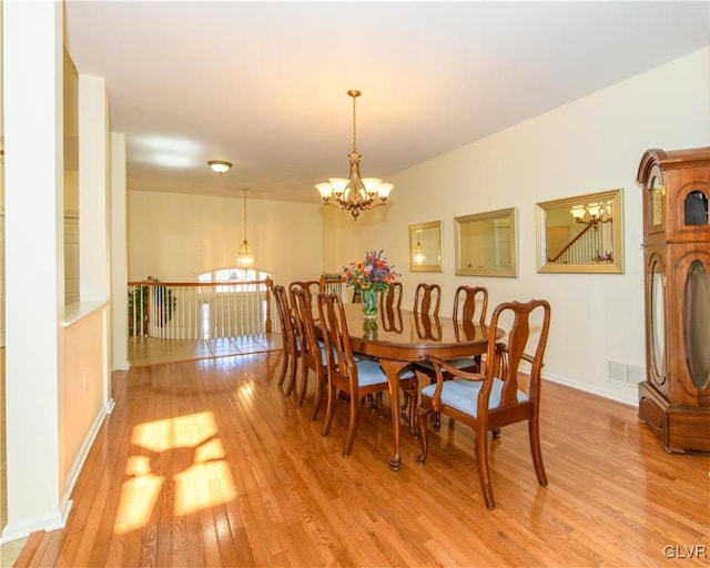 dining room featuring an inviting chandelier, light wood-style floors, visible vents, and baseboards