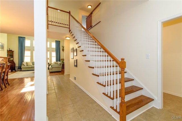 staircase with baseboards, a high ceiling, and wood finished floors