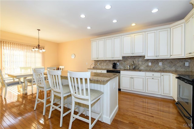 kitchen featuring light wood finished floors, tasteful backsplash, a center island, stainless steel appliances, and a sink