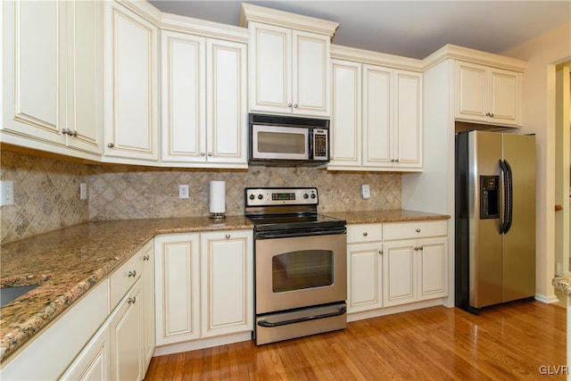 kitchen featuring backsplash, light wood-style flooring, appliances with stainless steel finishes, and cream cabinets