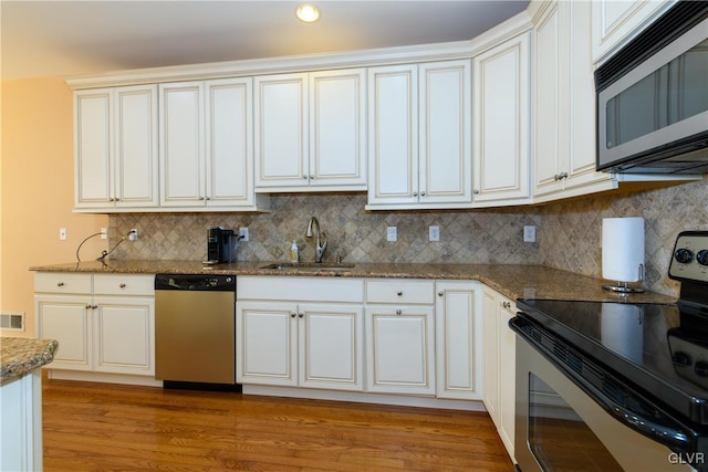 kitchen with visible vents, decorative backsplash, stone countertops, stainless steel appliances, and a sink