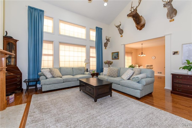 living room with high vaulted ceiling, an inviting chandelier, and wood finished floors