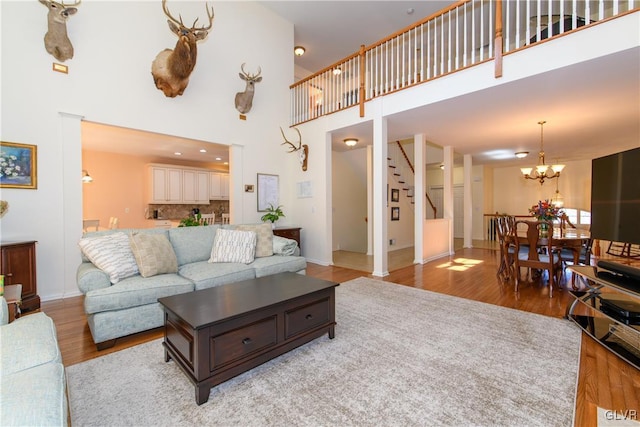 living room featuring light wood finished floors, baseboards, a chandelier, stairway, and a high ceiling