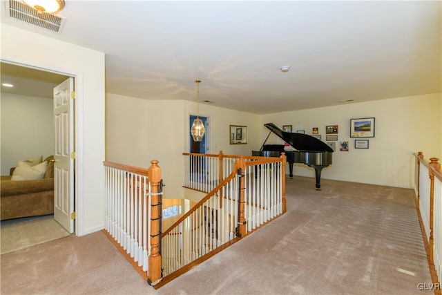 corridor with carpet flooring, an upstairs landing, and visible vents