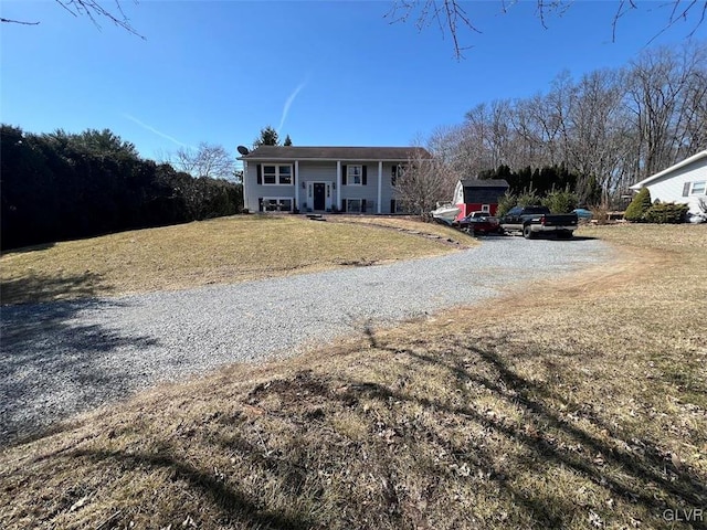 view of front of property featuring gravel driveway, a front yard, and a porch