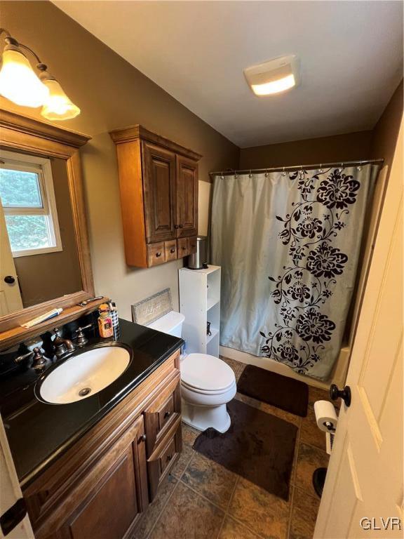 bathroom featuring vanity, toilet, and shower / bath combo with shower curtain