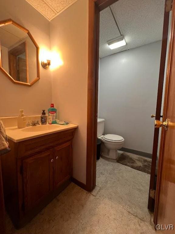 bathroom with a textured ceiling, toilet, vanity, and baseboards