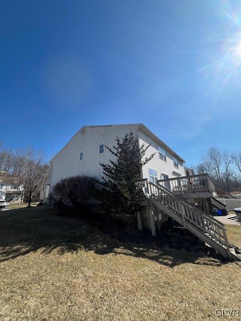 view of property exterior featuring a lawn, a deck, and stairs