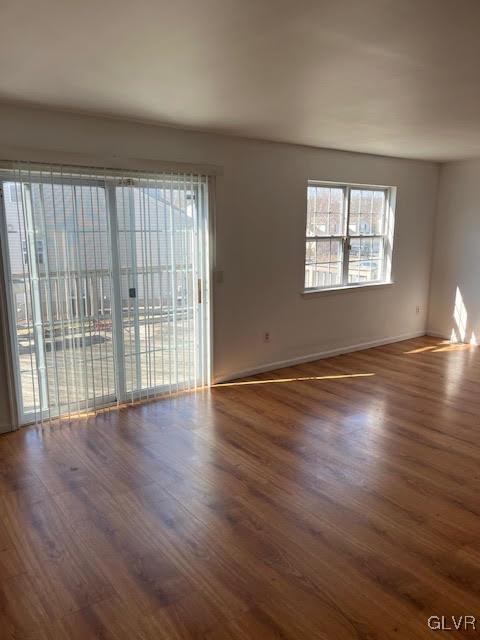 spare room featuring baseboards and wood finished floors