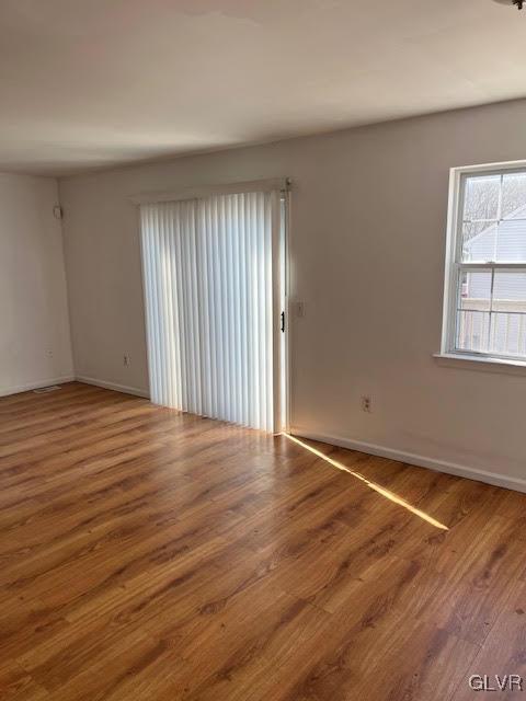 spare room with baseboards and wood finished floors