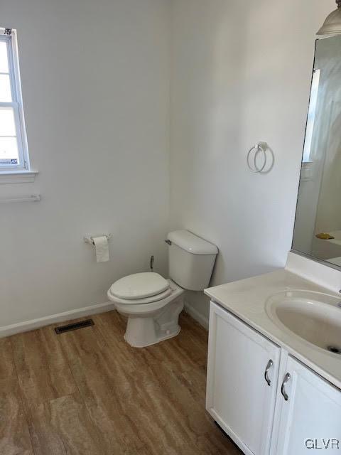 bathroom with visible vents, toilet, wood finished floors, baseboards, and vanity