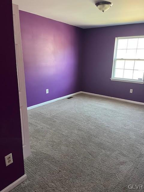 empty room with carpet flooring, baseboards, and visible vents