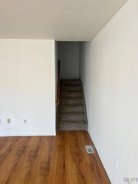 staircase with visible vents, baseboards, and wood finished floors