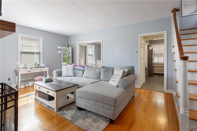 living area with light wood-style flooring, stairs, radiator heating unit, and baseboards