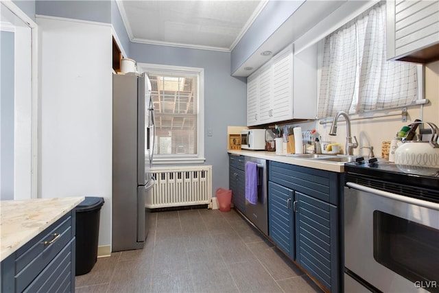 kitchen with radiator heating unit, a sink, appliances with stainless steel finishes, crown molding, and blue cabinets