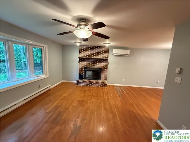 3965 Blacksmith Rd, Weisenberg Twp, PA 18066 - unfurnished living room featuring a wall unit AC, a brick fireplace, ceiling fan, wood finished floors, and baseboards
