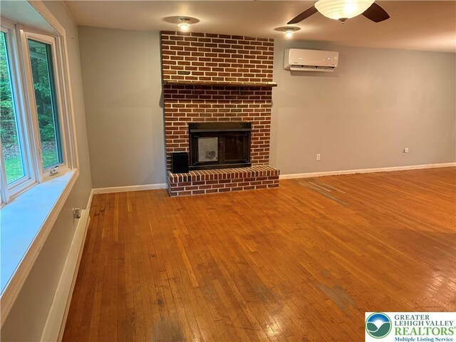 3965 Blacksmith Rd, Weisenberg Twp, PA 18066 - unfurnished living room with a wall mounted AC, hardwood / wood-style flooring, ceiling fan, a fireplace, and baseboards