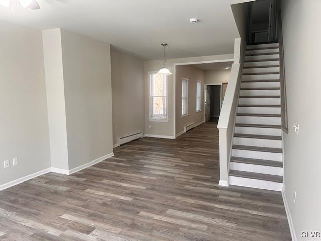 interior space featuring stairway, a baseboard heating unit, baseboards, and wood finished floors