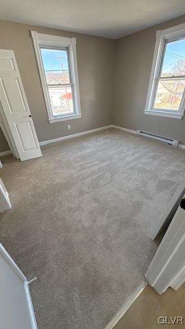 unfurnished bedroom featuring multiple windows, carpet, and a baseboard radiator