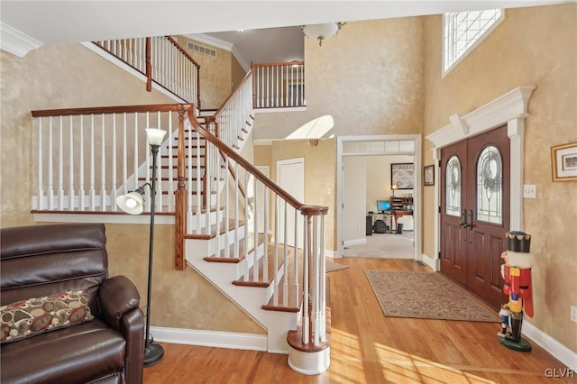 entrance foyer featuring visible vents, ornamental molding, wood finished floors, stairway, and baseboards