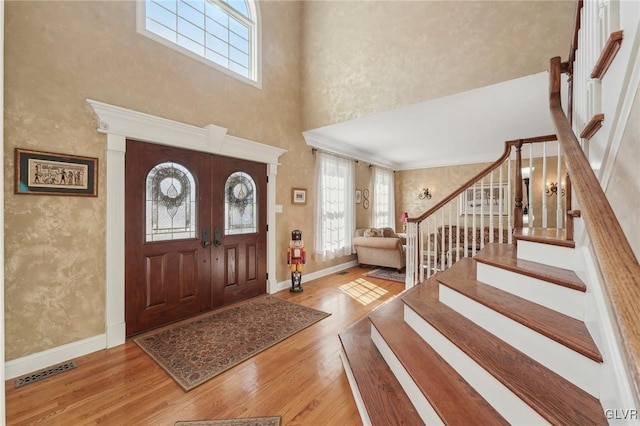 foyer entrance featuring visible vents, stairs, baseboards, and wood finished floors