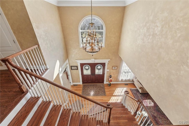 entrance foyer with stairway, wood finished floors, baseboards, an inviting chandelier, and a high ceiling