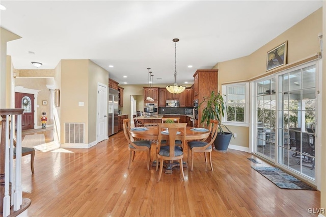 dining area with light wood-type flooring, visible vents, and baseboards