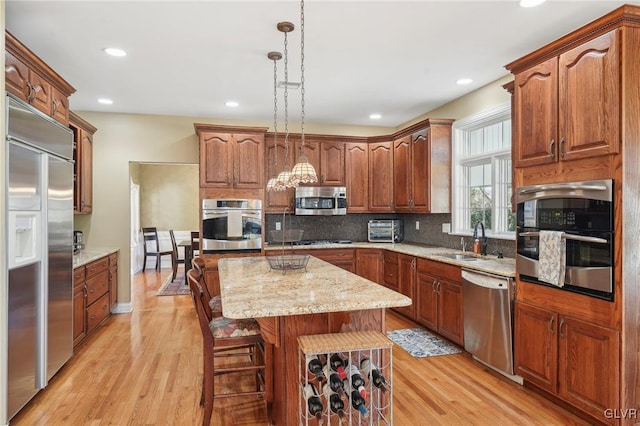 kitchen with pendant lighting, a sink, tasteful backsplash, a kitchen island, and appliances with stainless steel finishes