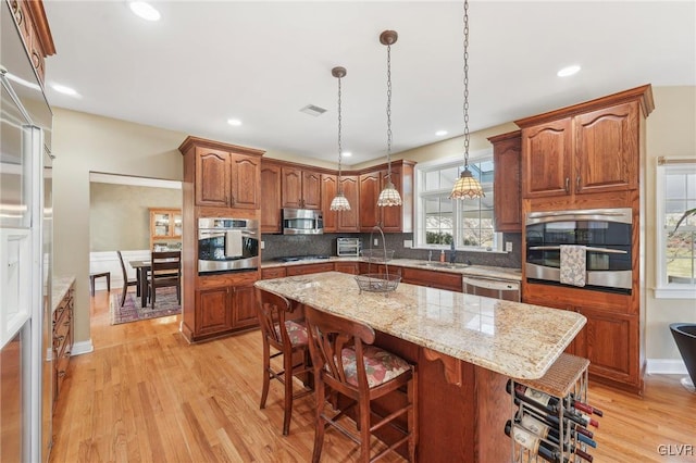 kitchen featuring light wood-style flooring, a kitchen island, backsplash, and stainless steel appliances