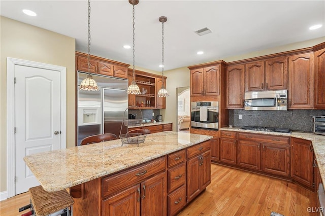 kitchen featuring visible vents, open shelves, light wood-style flooring, stainless steel appliances, and a center island