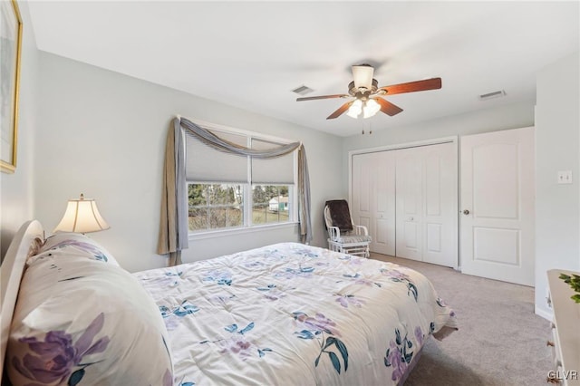 bedroom with visible vents, light colored carpet, a closet, and ceiling fan