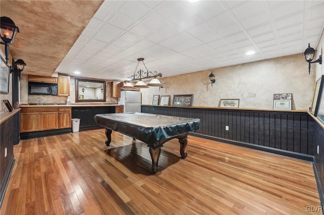 game room featuring light wood-type flooring, a wainscoted wall, and billiards