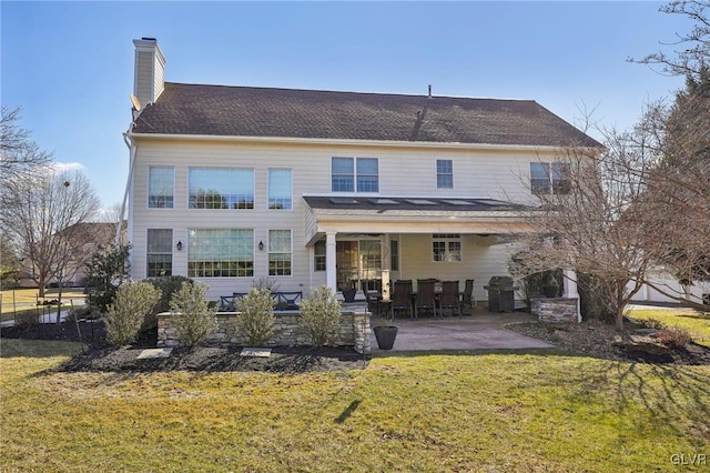 back of property featuring a patio area, a chimney, and a yard