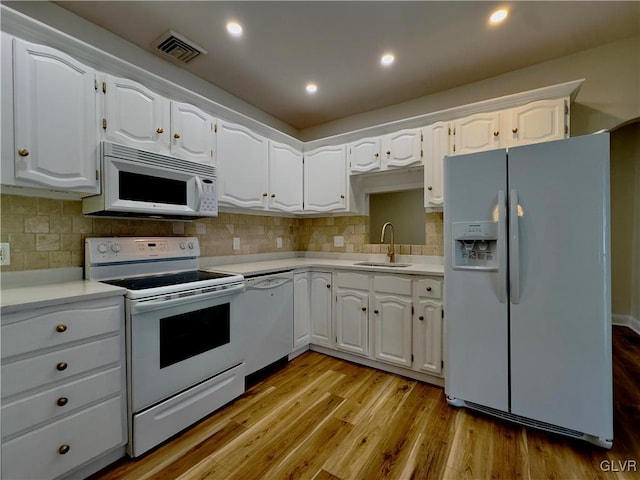 kitchen with white appliances, visible vents, light wood-style flooring, a sink, and light countertops