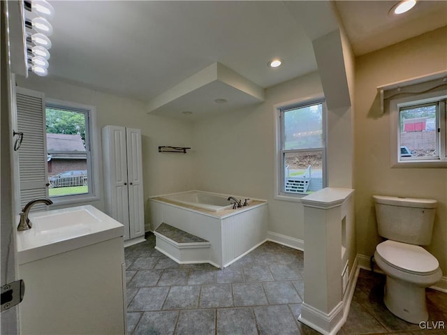 bathroom with a wealth of natural light, baseboards, toilet, and a garden tub