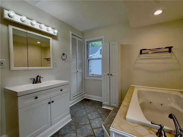 bathroom featuring vanity, baseboards, a closet, tile patterned floors, and a jetted tub