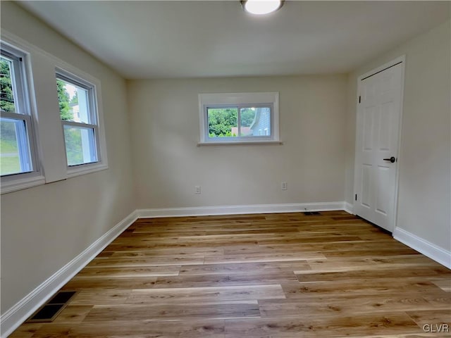 spare room with baseboards, wood finished floors, visible vents, and a healthy amount of sunlight