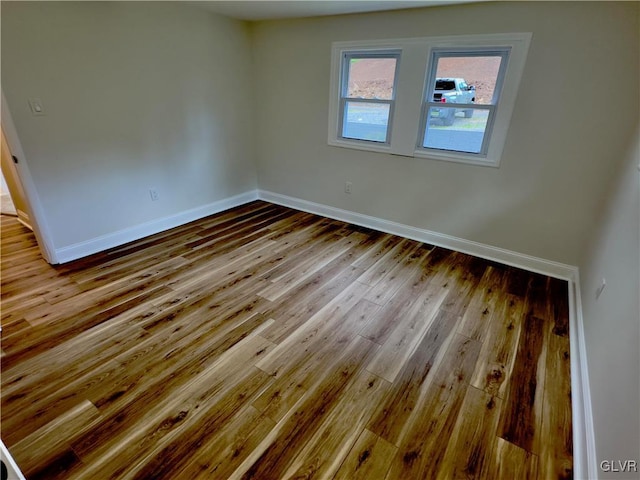 empty room with baseboards and wood-type flooring