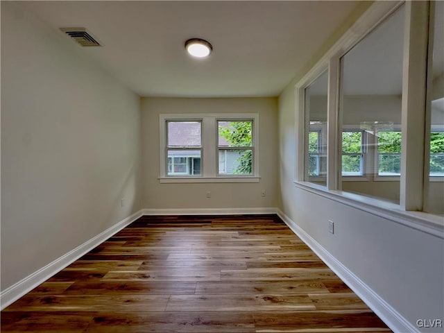 spare room featuring visible vents, baseboards, and wood finished floors