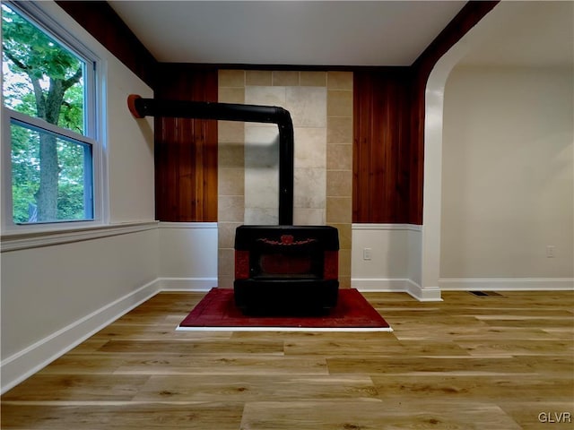 details with a wood stove, wood finished floors, baseboards, and arched walkways