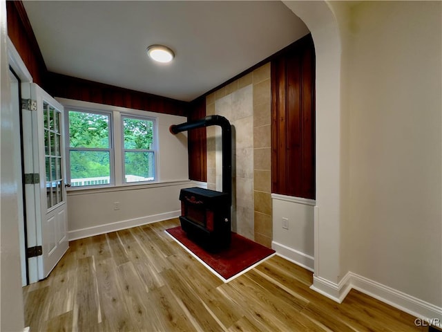 interior space featuring baseboards, arched walkways, wood finished floors, and a wood stove