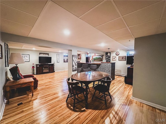 dining room with a paneled ceiling, baseboards, and light wood finished floors