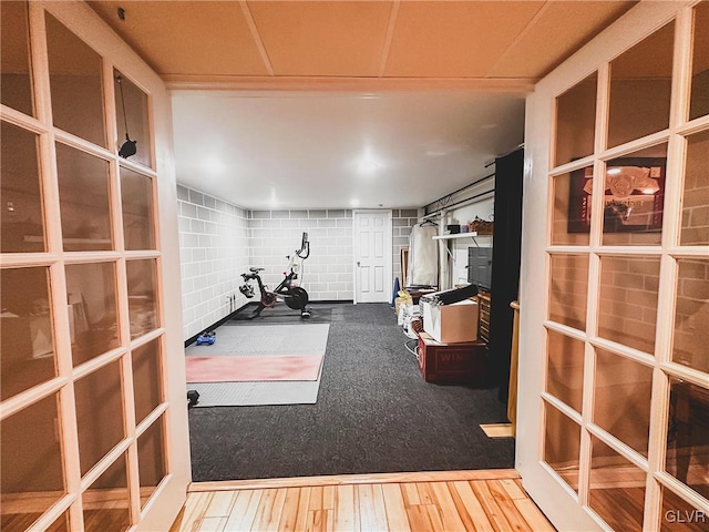 exercise area featuring wood finished floors and concrete block wall