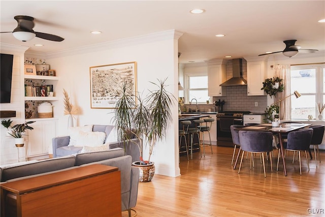 living area featuring crown molding, a wealth of natural light, and ceiling fan