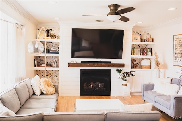 living area with visible vents, a fireplace, crown molding, and wood finished floors